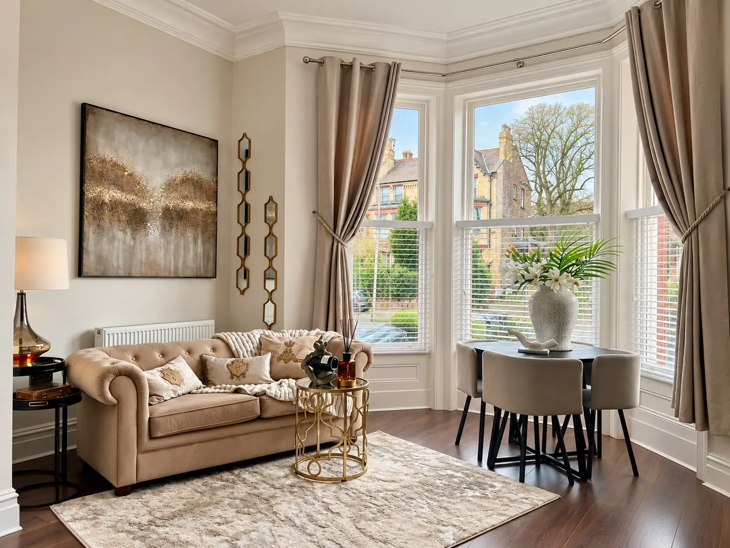 Lounge with a chesterfield sofa, gold side table and a large artwork beside a bay window