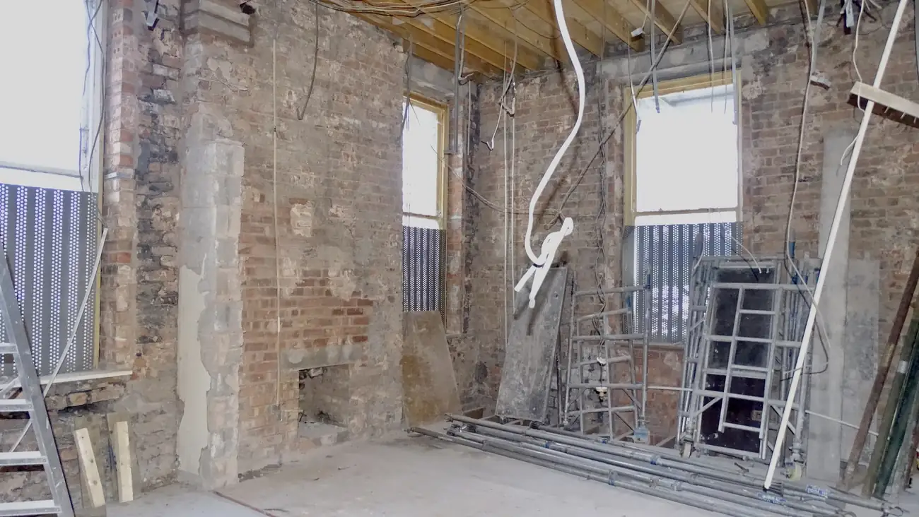 Before: the same room stripped back to bare brick, with the old fireplace opening