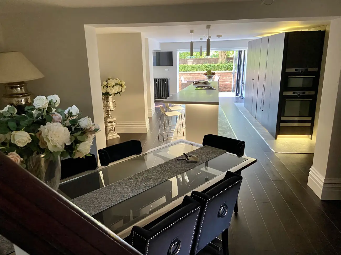 After: the dining table and kitchen island looking through open doors to the garden