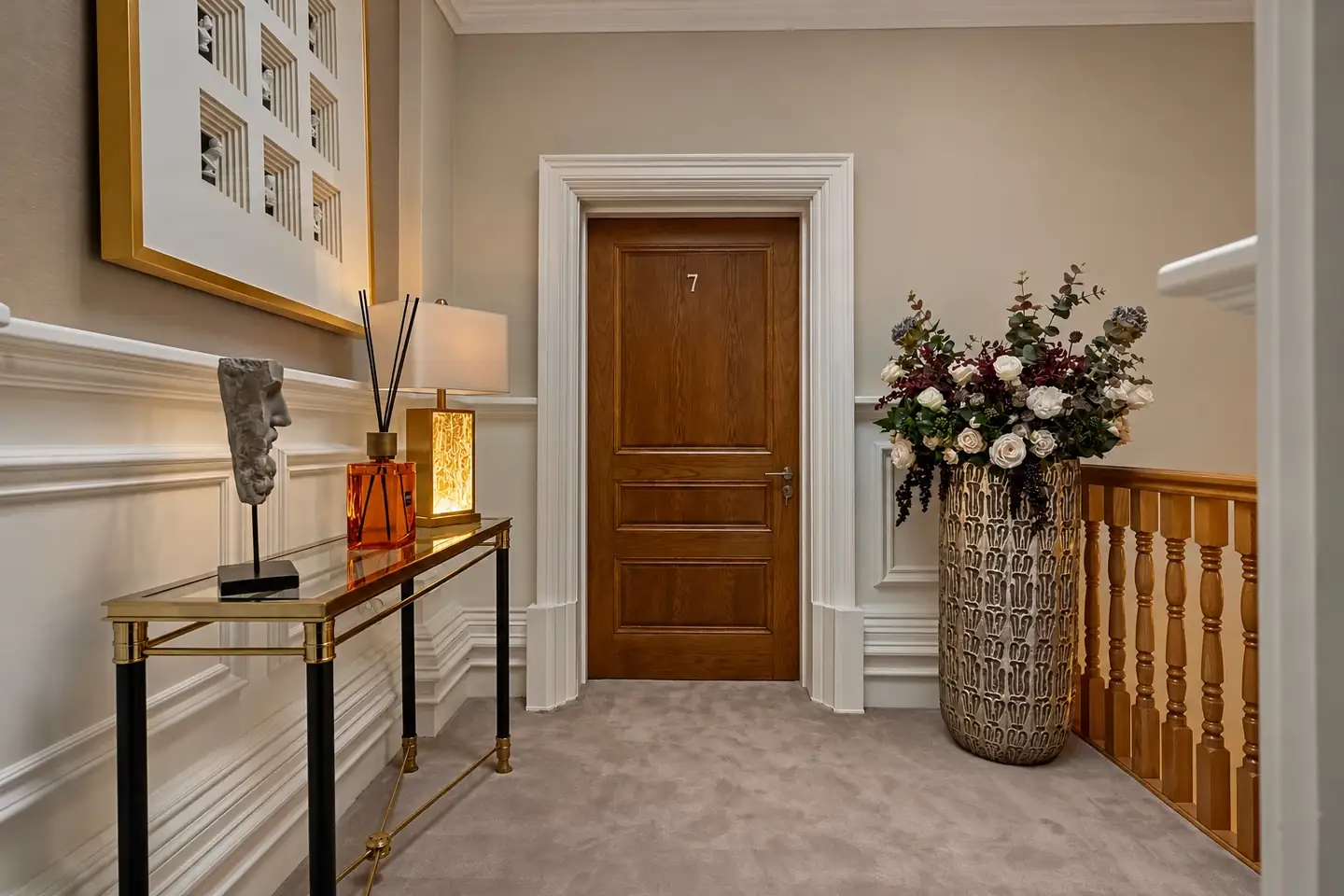 Landing outside apartment 7 with a brass console and a tall vase of flowers